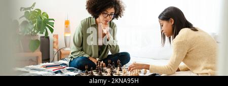 Schwarzes Mädchen und ihre Mutter spielen zu Hause Schach Stockfoto
