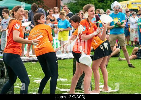 Ein Team aus vier jungen Frauen, von denen eine mit Vanillesauce bespritzt war, die während der World Custard Pie Championships in Maidstone, Großbritannien, Vanillesauce von einem Tisch warfen Stockfoto