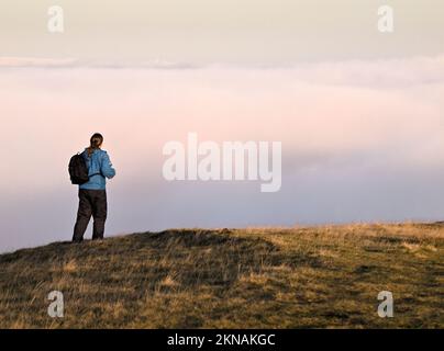 Eine Fotografin geht über den Talnebel auf dem Gipfel des Pule Hill, dem Marsden Moor Estate. Stockfoto