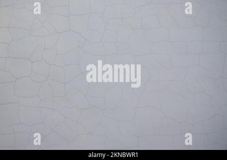 Gesprungener weißer alter Wandhintergrund. Horizontales Bild. Weiße schwarz graue Wand, Boden mit Rissen Textur Hintergrund Stockfoto