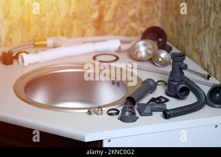 Klempner Werkzeuge und Wasserhahn bereit für die Installation in der Nähe von Waschbecken auf Arbeitsplatte in der Küche. Anschlüsse für den Einbau des Wasserhahns für den k Stockfoto