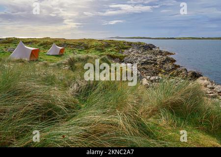 Zelte bei Sonnenuntergang mit dramatischem Wolkenhimmel am Clifton Beach in der Grafschaft Galway, westlicher Teil der Republik Irland Stockfoto