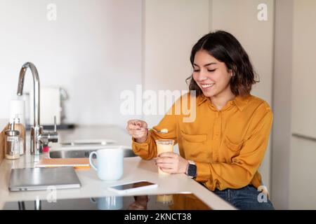 Junge Arabische Frau, Die Pudding Isst Und Kaffee Zum Frühstück Zu Hause Trinkt Stockfoto