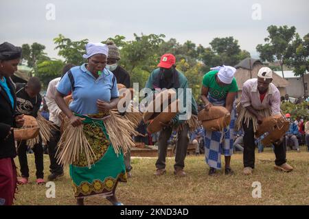 Eine Frau pfeift und tanzt vor exotischen, traditionellen Musikern, die große selbstgemachte Holzklappern spielen Stockfoto