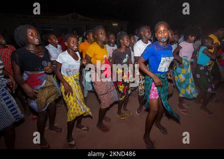 Abends singende und tanzende Mädchen in bunten Kleidern mit afrikanischen Wachsabdrücken Stockfoto