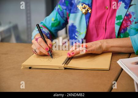 Unbekannte Schneiderin mit bunten Kleidern, die ein neues Layout zeichnen. Stockfoto