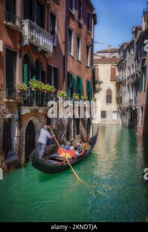 Touristen erfüllen eine Wunschliste entlang eines der vielen kleinen Seitenkanäle im historischen Venedig, Italien. Stockfoto