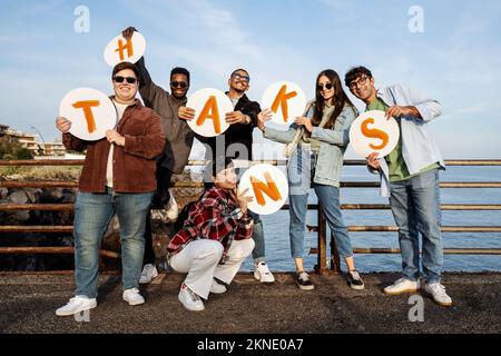 Das Porträt einer positiven Gruppe multiethnischer Jugendlicher vermittelt eine Dankesbotschaft mit dem Wort "danke", handgeschrieben in Großbuchstaben Stockfoto