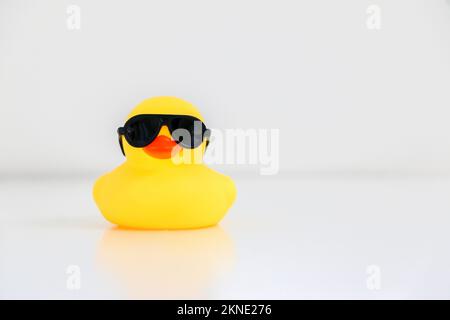 Coole kleine gelbe Gummiente mit schwarzer Sonnenbrille, Kopierbereich rechts. Das Konzept „Seien Sie klug, seien Sie cool“. Stockfoto