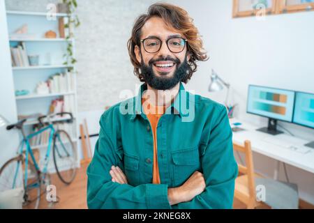 Porträt eines jungen kreativen Unternehmers, der im modernen Home Office vor der Kamera lächelt Stockfoto