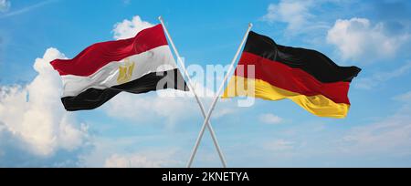 Zwei überkreuzte Flaggen Bundesrepublik Deutschland und Ägypten winken im Wind am bewölkten Himmel. Beziehungskonzept, Dialog, Reisen zwischen zwei Ländern Stockfoto