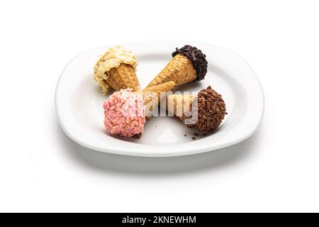 Eine Einzelaufnahme eines Tellers mit verschiedenen eiscremeförmigen Gebäckstücken auf einer Zapfen auf weißem Hintergrund Stockfoto