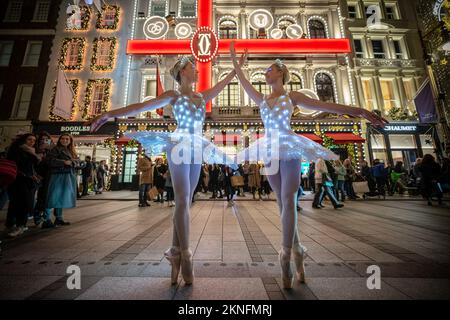 London, Großbritannien. 27.. November 2022. Weihnachtsballerinas: Die Zwillinge Abigail(R) und Lauren(L) Everard, beide Absolventen des klassischen Balletts der Theater-Tanzschule London Studio Centre (LSC), üben einige Bewegungen mit speziellem LED-Ballett-Tutus und Diaras unter der festlichen Stadtbeleuchtung. Kredit: Guy Corbishley/Alamy Live News Stockfoto