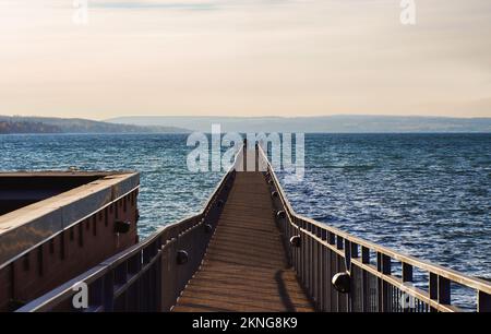 Skaneateles Pier am Skaneateles Lake in der Finger Lakes Region im Bundesstaat New York an einem kalten Herbstmorgen mit zwei unbekannten Männern beim Angeln Stockfoto