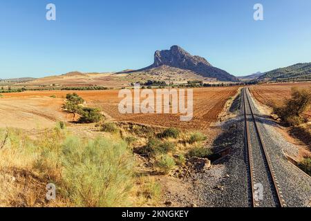 In der Nähe von Antequera, Provinz Malaga, Andalusien, Südspanien. Felder und Bahnlinie direkt außerhalb der Stadt mit La Peña de los Enamorados, (Lovers' R Stockfoto