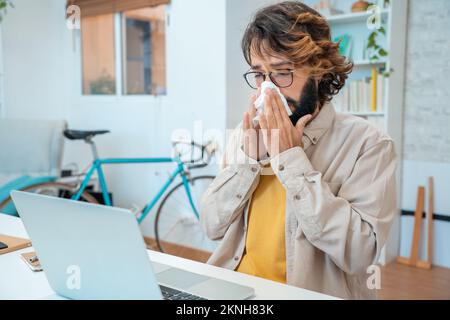 Krank bei der Arbeit junger Mann bekam Grippeallergie Niesen bläst Wischen der Nase im Gewebe Stockfoto