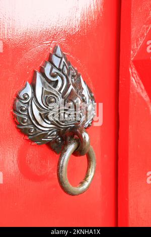 Nahegelegene rote Tür - frisch bemalte rote Vordertür mit mythischer Kreatur Kopf Bronze Knocker Stockfoto