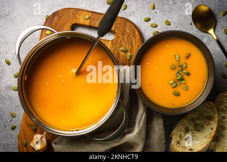 Kürbissuppe im Topf am Steintisch. Stockfoto