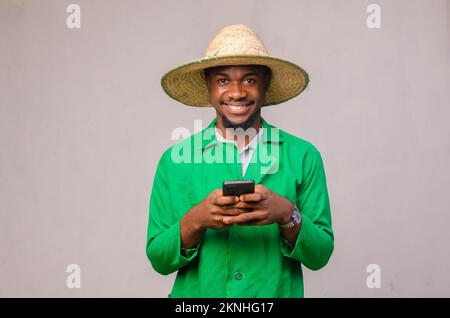 Ein fröhlicher afroamerikanischer Mann in einem grünen Hemd, der ein Handy benutzt Stockfoto