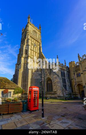 Cirencester, Großbritannien - 17. Oktober 2022: Blick auf die Kirche St. John der Täufer, rote Telefonzelle und Wegweiser, in Cirencester die Cotswolds reg Stockfoto