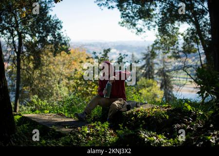 Der Mann im Park gießt Wasser aus einer Thermoskanne in einen Mate Becher. Stockfoto