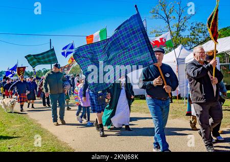 Bei der Parade der Clan-Tartane beim alljährlichen Celtic Music Festival und den Scottish Highland Games in Gulfport, Mississippi, tragen die Menschen Tartane mit sich. Stockfoto