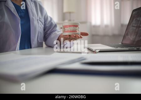 Nahhand einer Praxiszahnärztin. Die Halteprothesenuntersuchung. Stockfoto