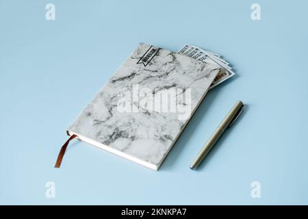 Steigende Lebenshaltungskosten, Inflation, Finanz- und Wirtschaftskrisenkonzept. Notizbuch mit Geldscheinen in Dollarpapier auf blauem Hintergrund. Stockfoto