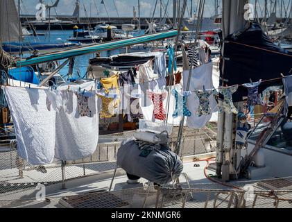 Gewaschene Kleidung zum Trocknen an der Wäscheleine auf einem Segelboot. Stockfoto