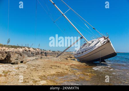 Eine Yacht, die auf dem felsigen Mantel von Sizilien, Italien, auf Grund läuft Stockfoto