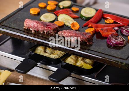 schweizer Raclette mit Fleisch und Gemüse Stockfoto
