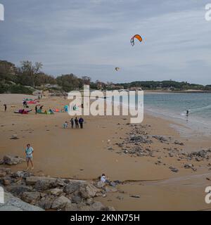 Santander, Spanien - 31. Oktober 2022: Kitesurfer und Badende am Strand Playa de los Peligros, Santander, Kantabrien Stockfoto