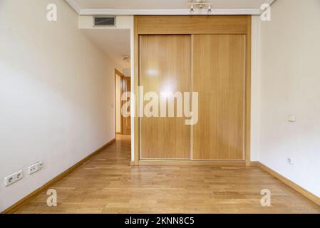 Schlafzimmer mit eingebautem Kleiderschrank mit Schiebetüren aus Eiche in einem Zimmer mit Klimaanlage und Fußboden aus französischer Eiche Stockfoto