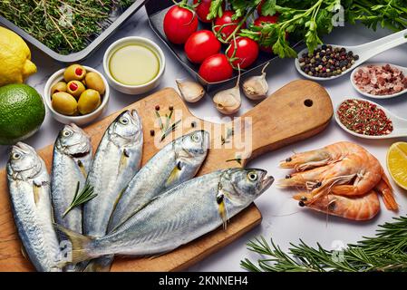 Hintergrundinformationen zu frischen Fischgerichten. Verschiedene Meeresfrüchte, Garnelen und roter Kaviar. Fisch zum Kochen mit Kräutern, Gemüse und Gewürzen auf weißem Hintergrund isoliert Stockfoto
