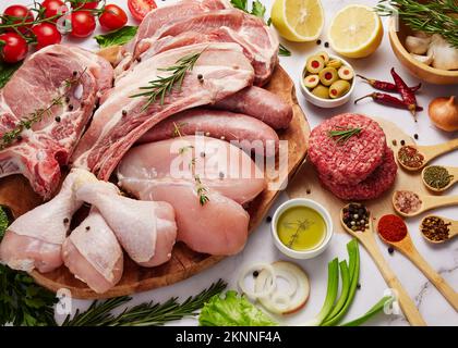 Hintergrundinformationen zu Frischfleisch und Lebensmitteln. Schweinefleisch, Rippchen, Burger mit Rindersteak, Hühnerfilet und Nuggets mit Kräutern, Gemüse und Gewürzen isoliert auf weißem Backgro Stockfoto