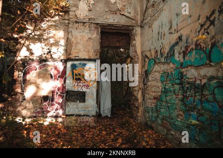 Ein komisches Bild des Mannes in Geisterkostümen und Sonnenbrillen in einem verlassenen Gebäude Stockfoto