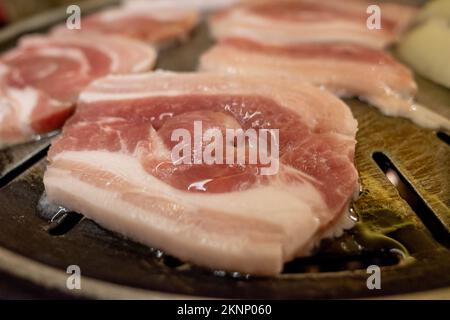 Selektiver Fokus und Nahaufnahme von geschnittenem Schweinebauch werden auf der Grillpfanne gegrillt. Stockfoto