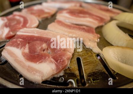 Selektiver Fokus und Nahaufnahme von geschnittenem Schweinebauch werden auf der Grillpfanne gegrillt. Stockfoto