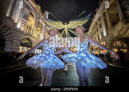 London, Großbritannien. 27.. November 2022. Weihnachtsballerinas: Die Zwillinge Abigail(L) und Lauren(R) Everard, beide haben ihren Abschluss in klassischem Ballett an der Theater-Tanzschule des London Studio Centre (LSC) gemacht und üben einige Moves mit speziellem LED-Ballett-Tutus und Diaras unter der festlichen Beleuchtung der Regents Street. Kredit: Guy Corbishley/Alamy Live News Stockfoto