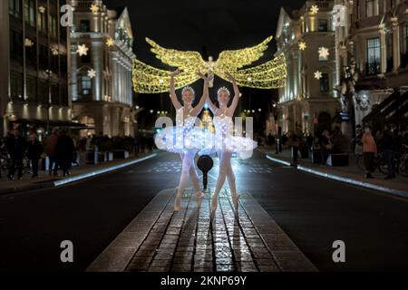 London, Großbritannien. 27.. November 2022. Weihnachtsballerinas: Die Zwillinge Abigail(R) und Lauren(L) Everard, beide Absolventen des klassischen Balletts an der Theater-Tanzschule des London Studio Centre (LSC), üben einige Bewegungen mit speziellem LED-Ballett-Tutus und Diaras unter der festlichen Beleuchtung der Regents Street. Kredit: Guy Corbishley/Alamy Live News Stockfoto