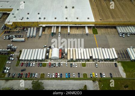 Luftaufnahme eines großen kommerziellen Vertriebszentrums mit vielen Lkw, die Einzelhandelsprodukte für den weiteren Versand entladen und hochladen. Weltwirtschaft Stockfoto