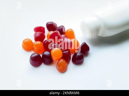 Gruppe roter, orangefarbener und violetter Multivitamingummi mit isolierter Flasche auf weißem Hintergrund Stockfoto