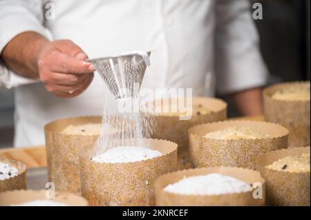 Konditorin serviert traditionelle italienische Panettones mit Puderzucker. Hochwertige Fotografie. Stockfoto