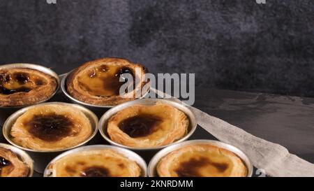 Reihen frisch gekochter Eiertörtchen, traditionelles portugiesisches Dessert, Pastell de nata, Puddingtörtchen auf Metalltablett Stockfoto