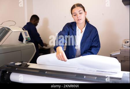 Weibliche Mitarbeiterin in einer Druck- und Pressezentar-Prüfung der Druckqualität Stockfoto