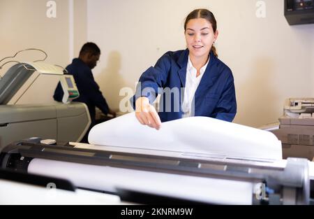 Weibliche Mitarbeiterin in einer Druck- und Pressezentar-Prüfung der Druckqualität Stockfoto