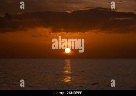 Dramatische rote Meereswellen bei Sonnenuntergang mit weichem, dunklem Meerwasser am Abend Stockfoto