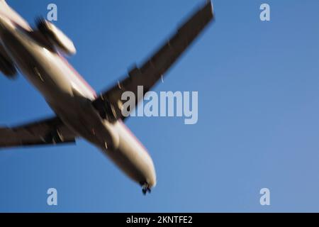 Unterseite eines kommerziellen Jet-Flugzeugs im Flug mit Bewegungseffekt. Stockfoto