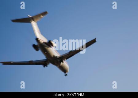 Unterseite eines kommerziellen Jet-Flugzeugs im Flug mit Bewegungseffekt. Stockfoto