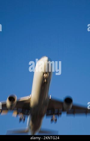 Unterseite eines kommerziellen Jet-Flugzeugs im Flug mit Bewegungseffekt. Stockfoto